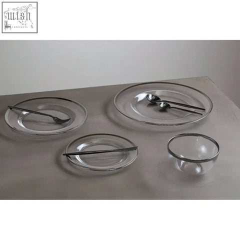 Clear glass charger plate with sleek silver rim paired with matching black utensils for stylish dining