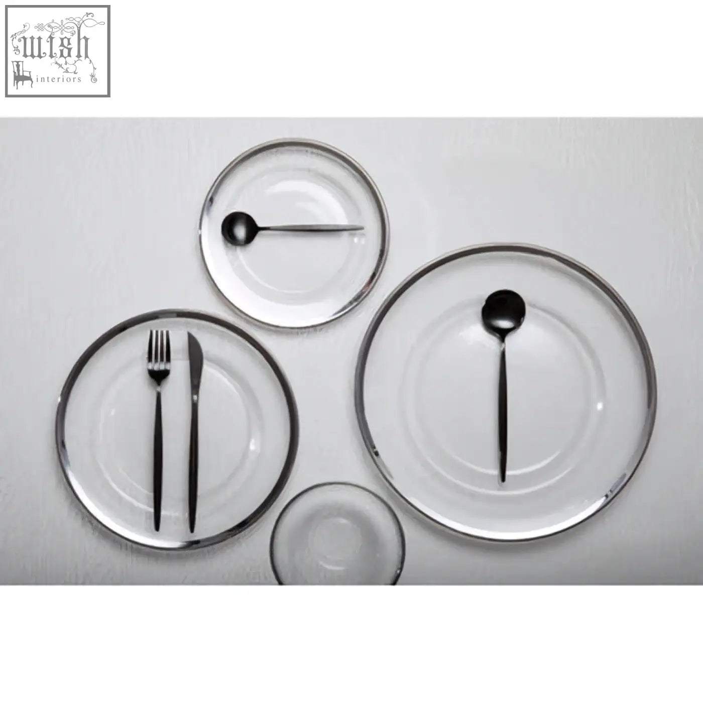 Set of minimalist glass charger plates with sleek black cutlery and elegant silver rim for stylish dining table settings