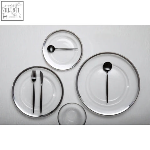 Set of minimalist glass charger plates with sleek black cutlery and elegant silver rim for stylish dining table settings