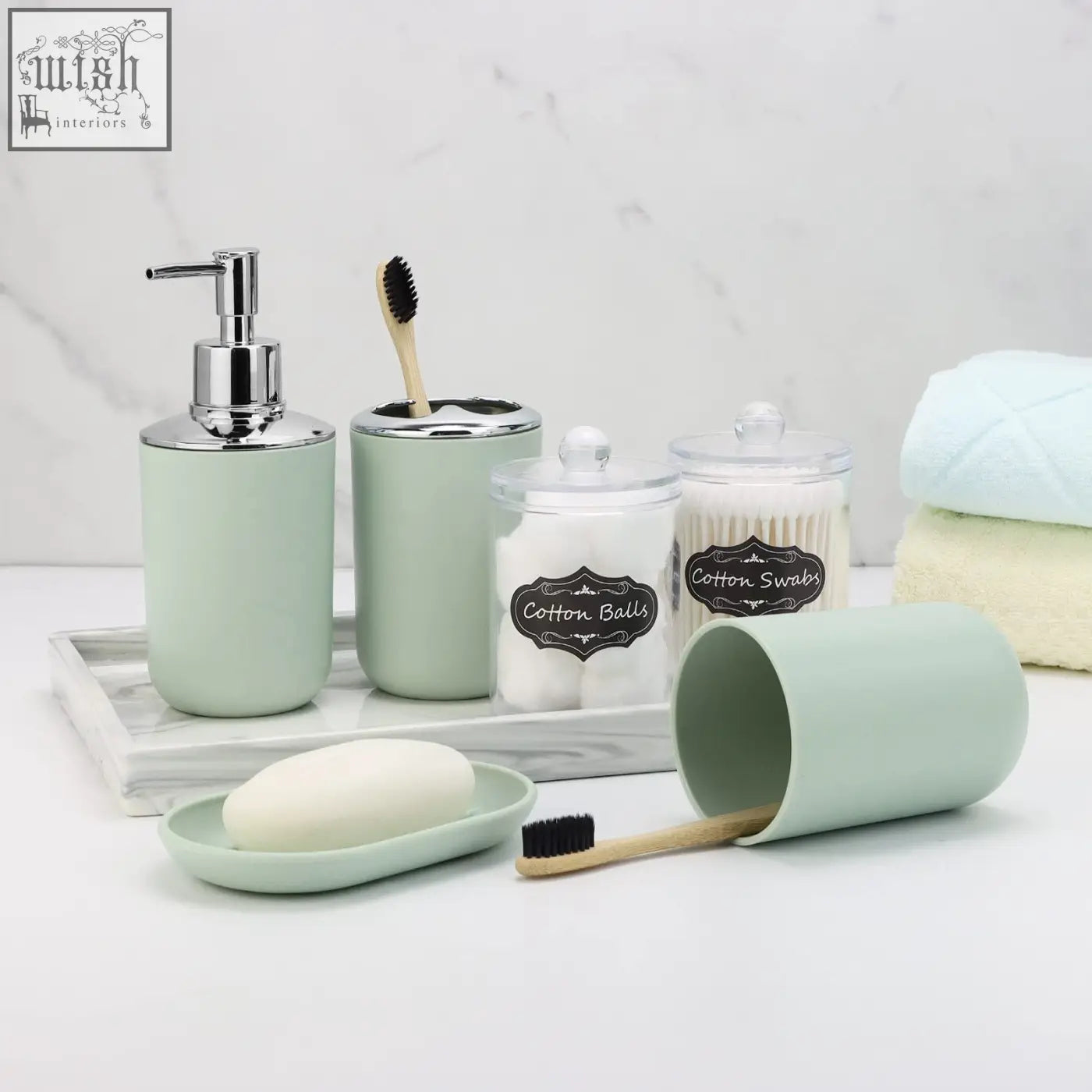 Mint green ceramic bathroom accessories set with chrome accents and labeled containers for soap, cotton, swabs, and toothbrushes