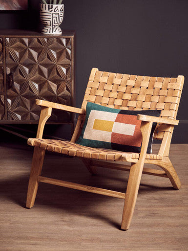 Inca armchair with woven rattan, leather straps, american oak frame, and colorful geometric pillow for a cozy touch