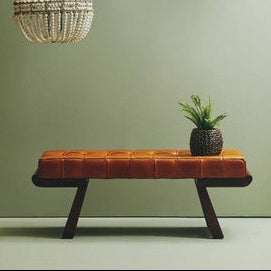 Orange tufted leather bench with angular wooden base and dark wooden legs perfect seating solution