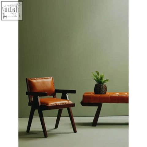 Brown leather armchair with tan leather upholstery and teak frame dining chair featuring contrasting stitching