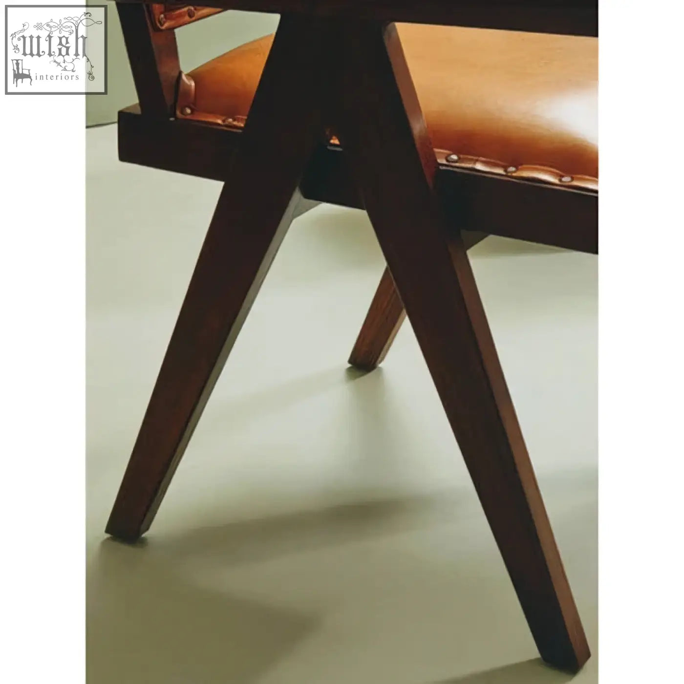 Dark wood chair with tan leather seat and visible stitching in a teak frame dining chair design