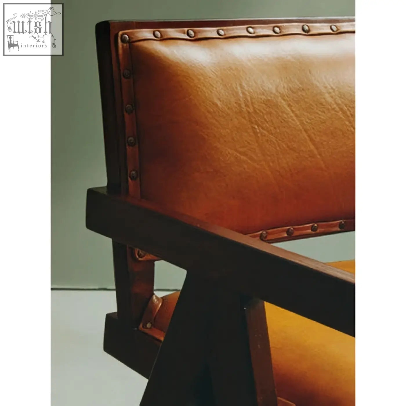 Tan leather dining chair with teak frame and brass nailhead trim perfect for frame dining setups