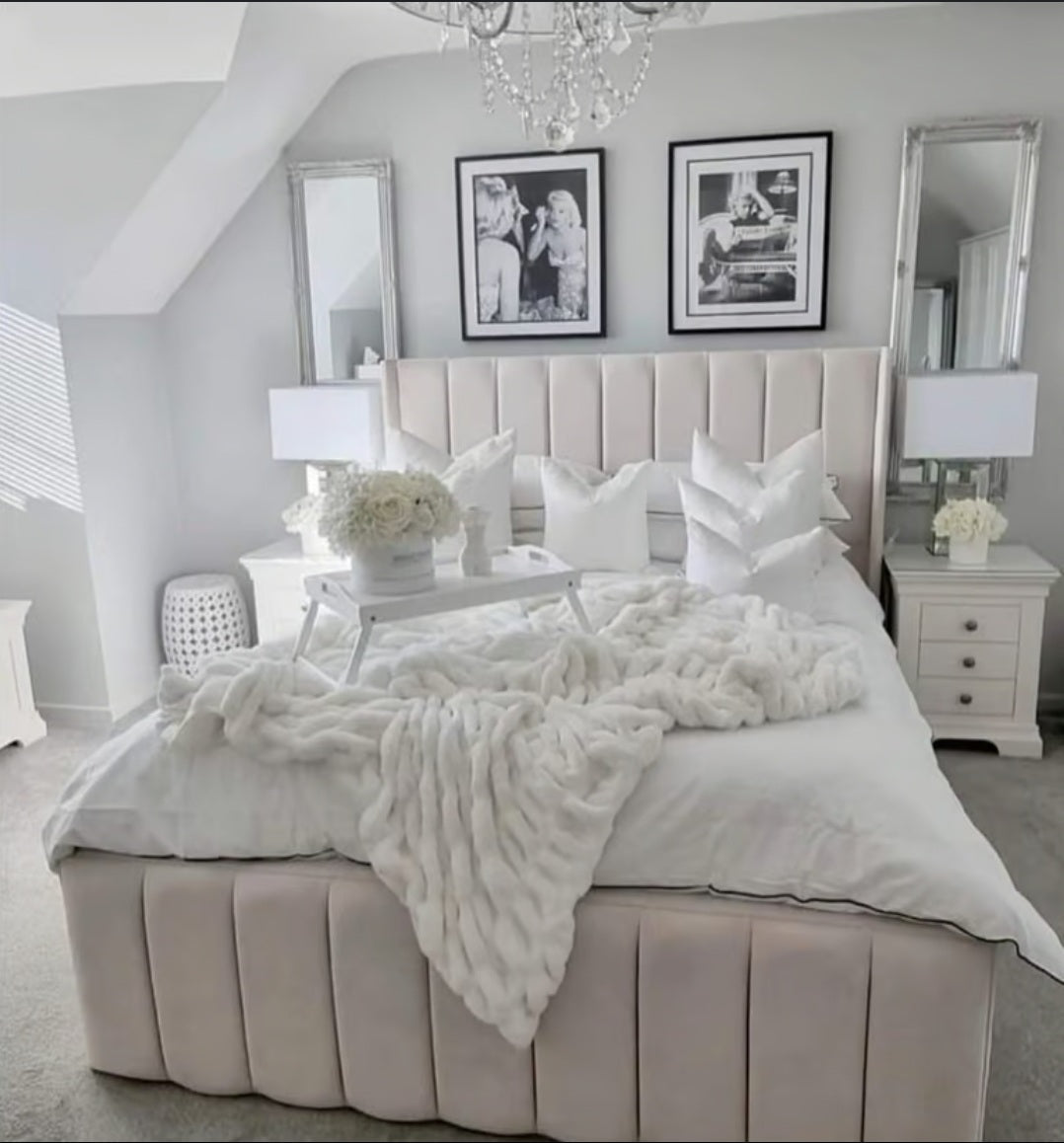 Beige tufted upholstered indiana bed frame with solid wooden base and white plush knit throw at the footboard