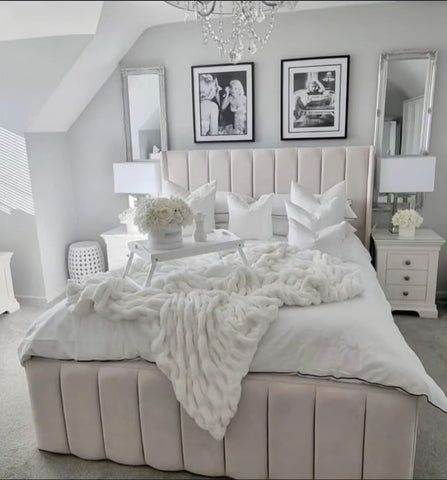 Beige tufted upholstered indiana bed frame with solid wooden base and white plush knit throw at the footboard
