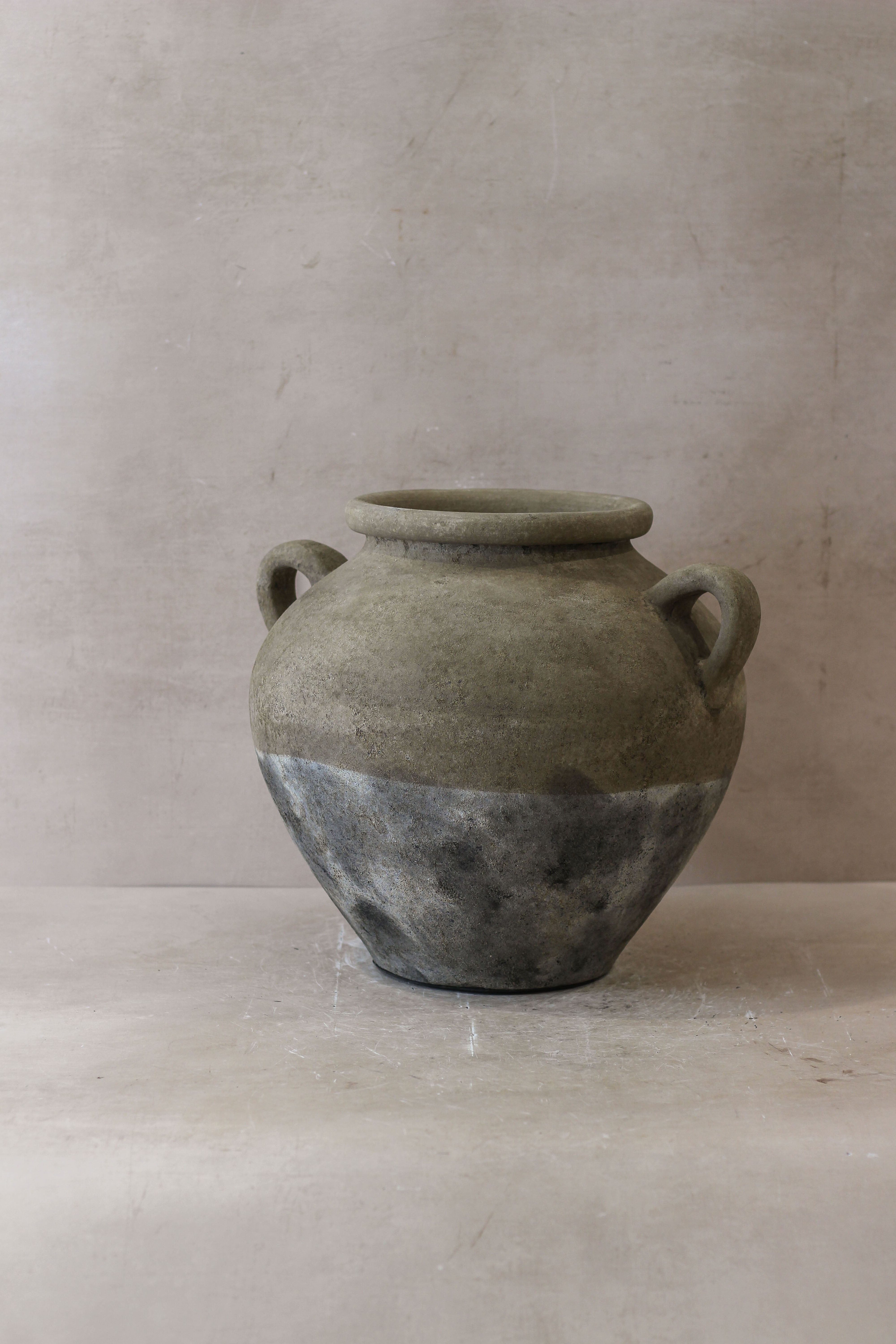 A rustic two-handled ceramic indonesia pot no 27 with matte gray finish and dark metallic band on lower half