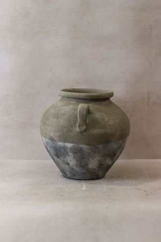 A rustic two-toned ceramic indonesia pot no 27 with matte gray top and speckled dark bottom featuring a loop handle