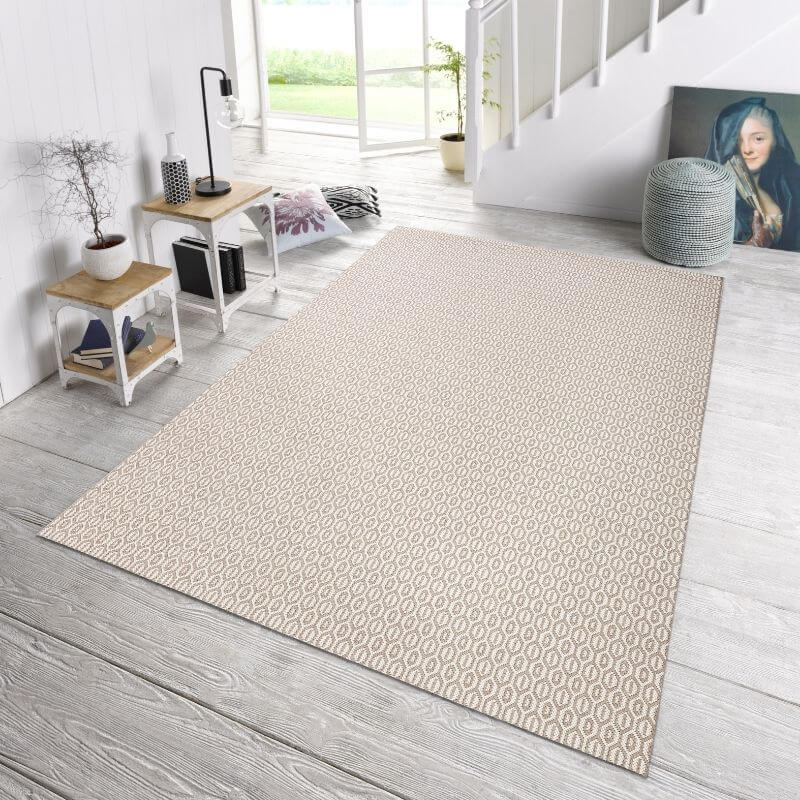Beige indoor outdoor coin rug with subtle light gray geometric pattern laid on wooden floor for indoor outdoor use