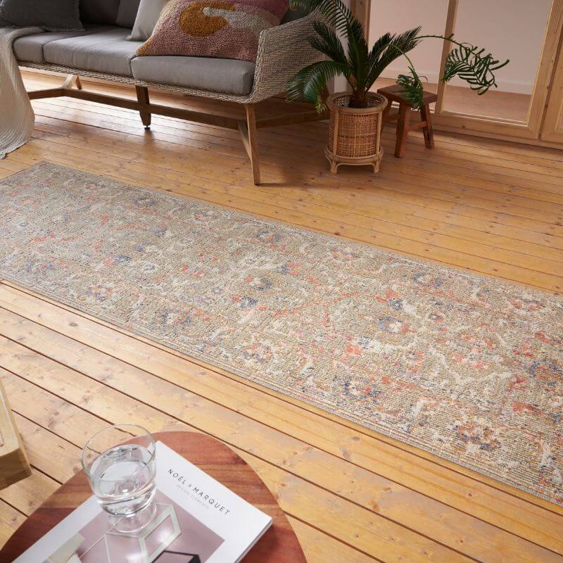 A long indoor outdoor port said rug with distressed medallion faded floral patterns in beige pink and dusty blue tones