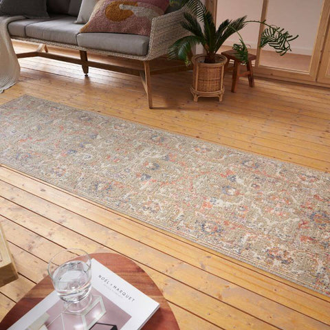 A long indoor outdoor port said rug with distressed medallion faded floral patterns in beige pink and dusty blue tones