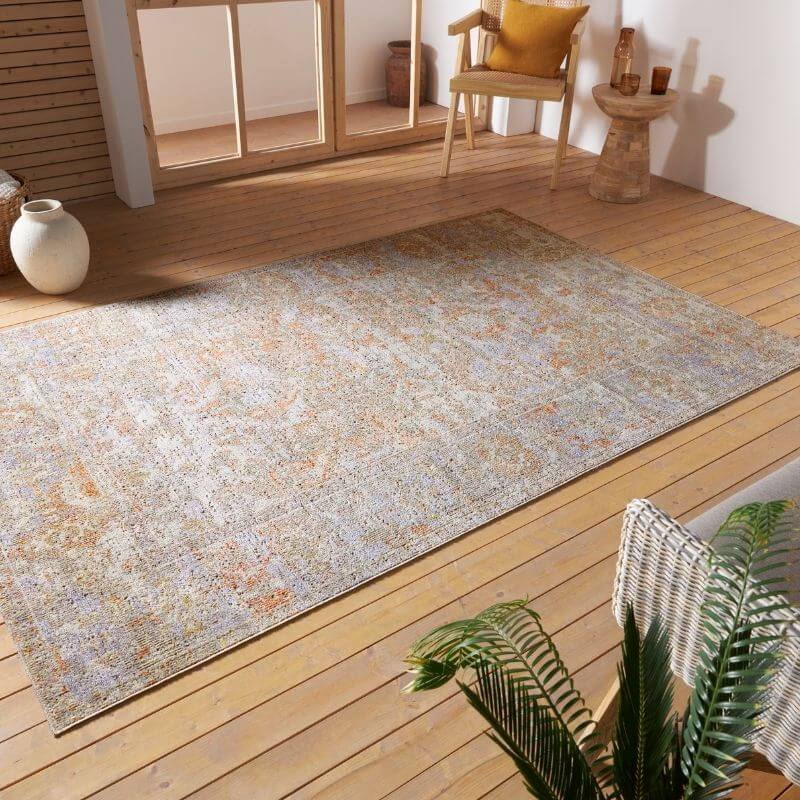 A rectangular indoor outdoor port said rug with a faded beige and muted orange distressed medallion pattern on gray