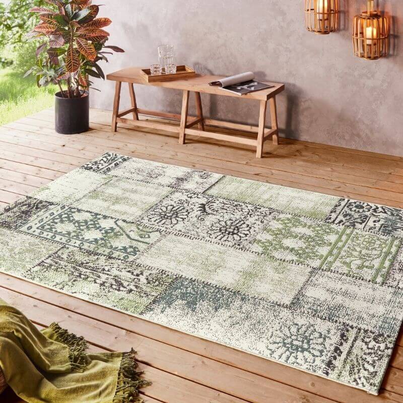 Indoor outdoor symi rug patchwork style with faded green cream colors and black floral patterns on each segment
