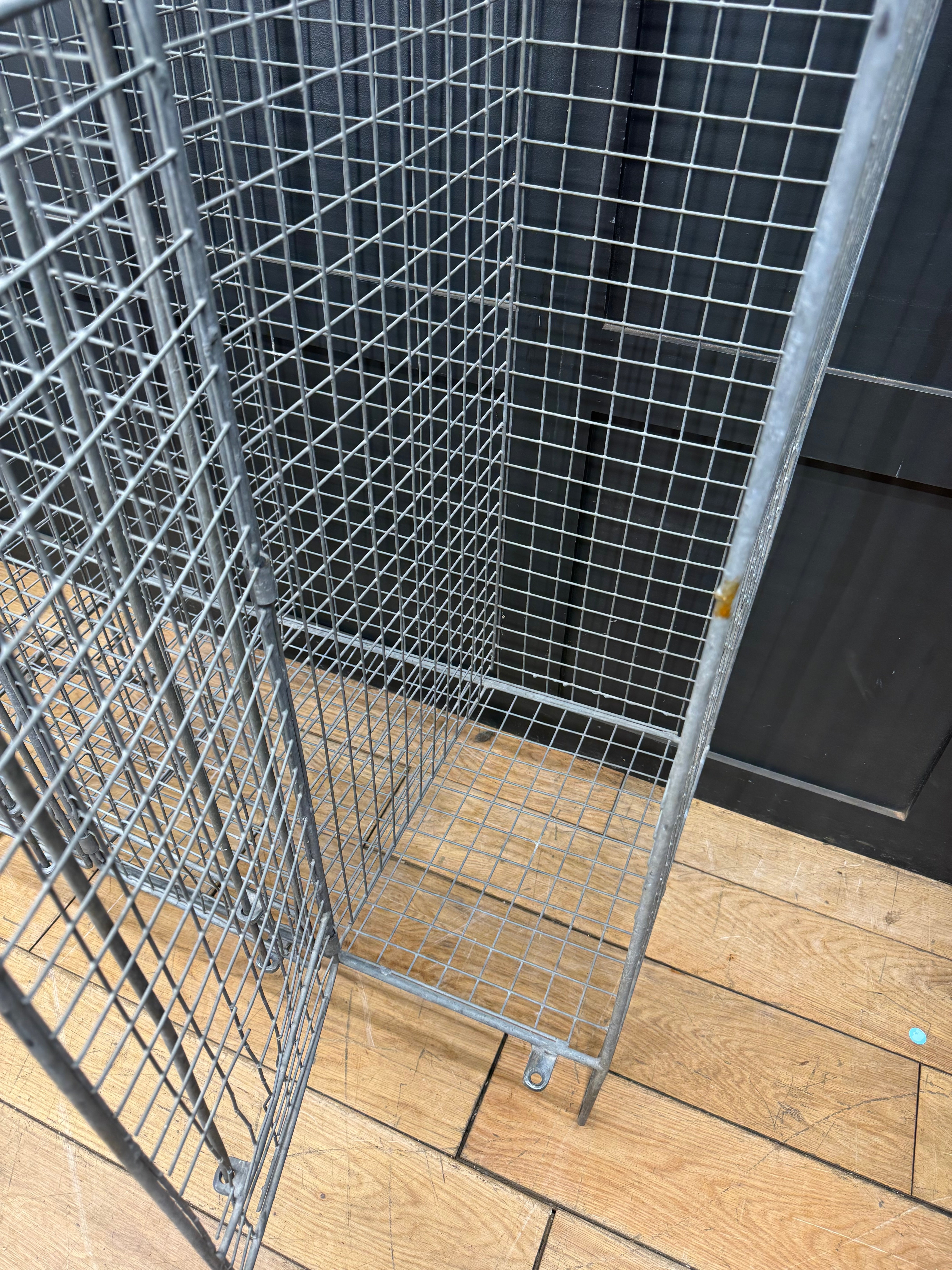 Silver metal wire mesh storage cage with grid pattern and wheels for industrial vintage three door locker cabinet