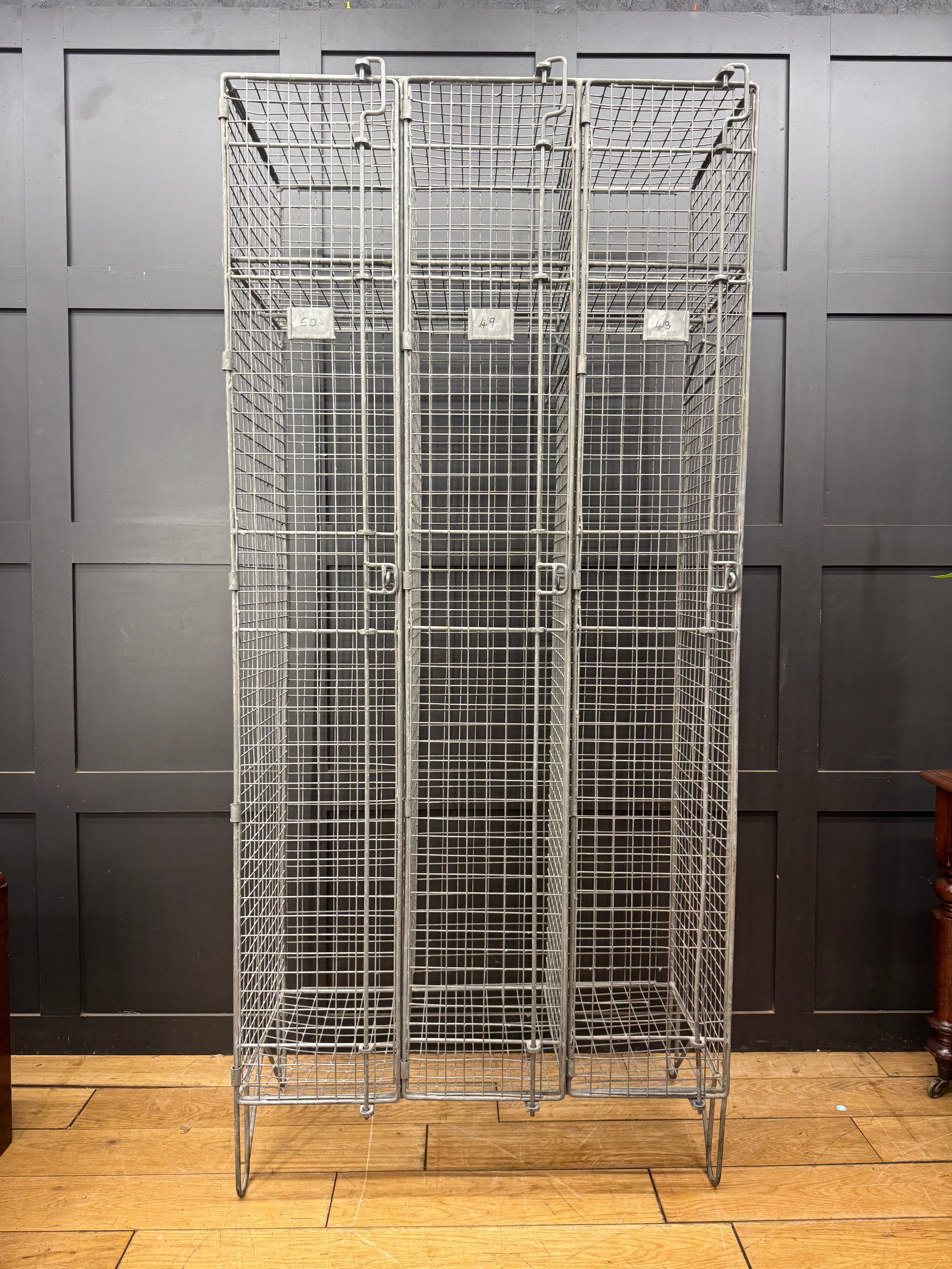 Industrial vintage wire mesh storage cabinet with three lockable doors and wheeled base for easy mobility