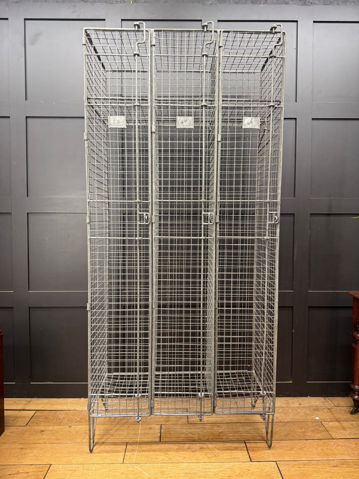 Industrial vintage wire mesh storage cabinet with three lockable doors and wheeled base for easy mobility