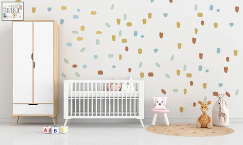 White wooden crib with vertical slats and rounded corners next to irregular shape dots wall decals for nursery decor
