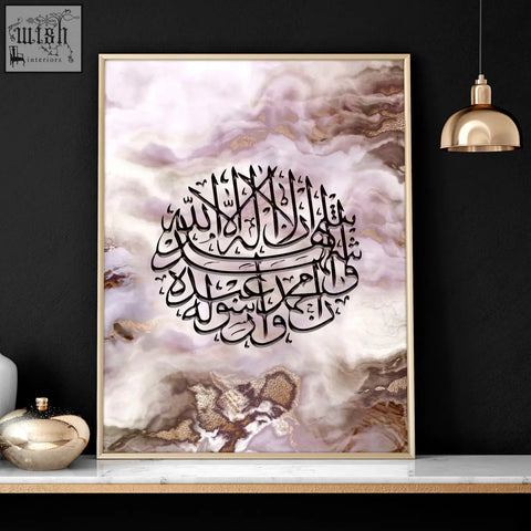 A framed islamic wall art piece with black arabic calligraphy on a marbled pink white and gold background