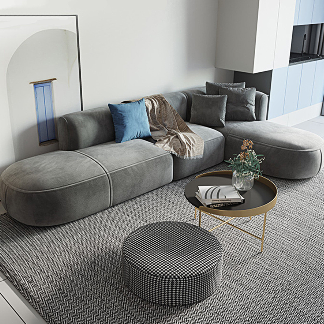 Modern grey velvet isolde three seater corner sofa with plush cushions and a blue throw pillow