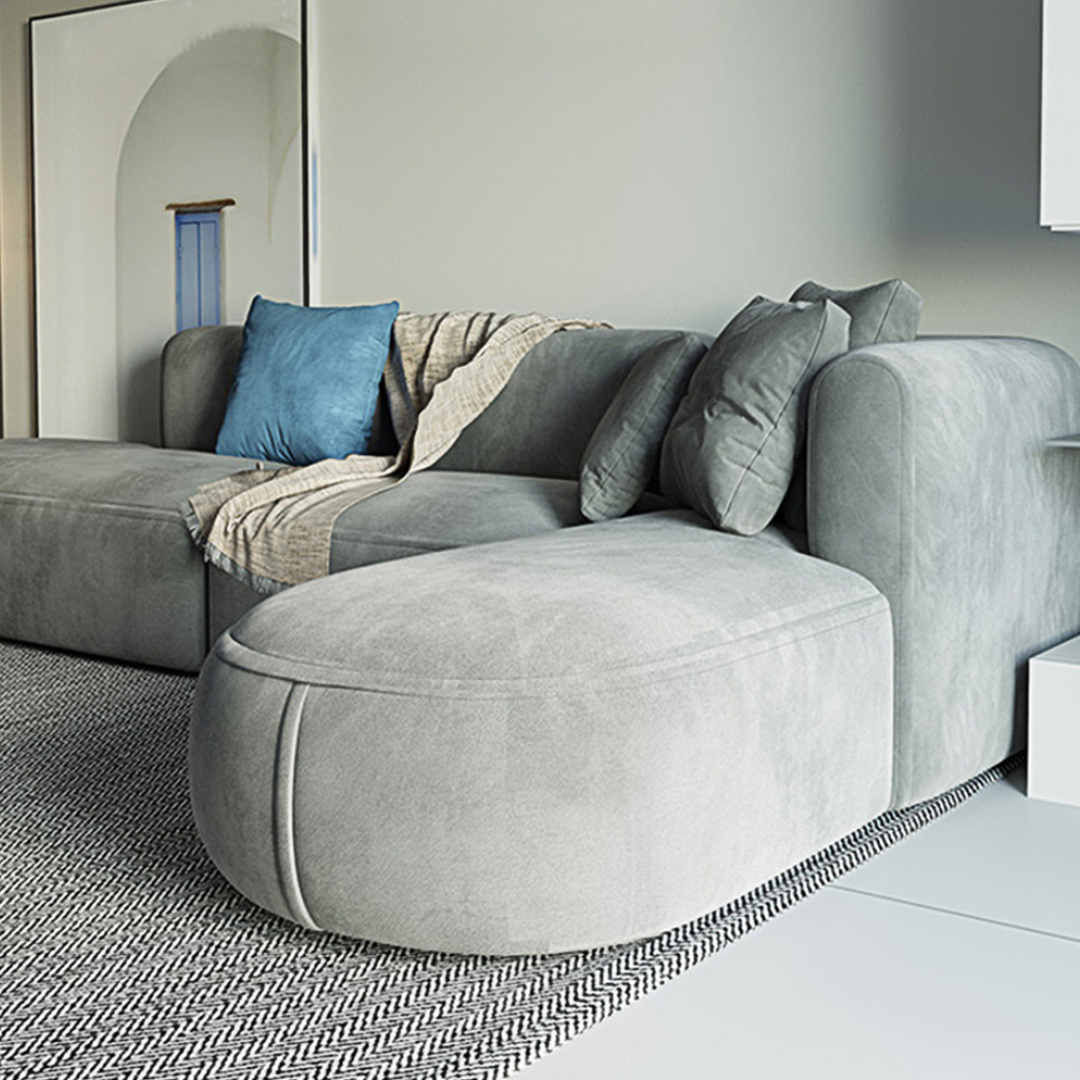 Modern gray suede isolde three seater corner sofa with plush cushions and blue throw pillow in grey velvet