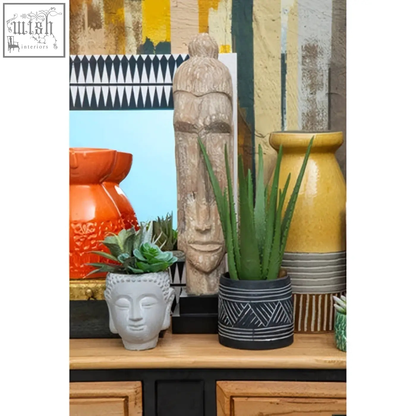 Gray ceramic buddha head planter with succulent displayed below issey wall mirror as a stylish focal point on white wall