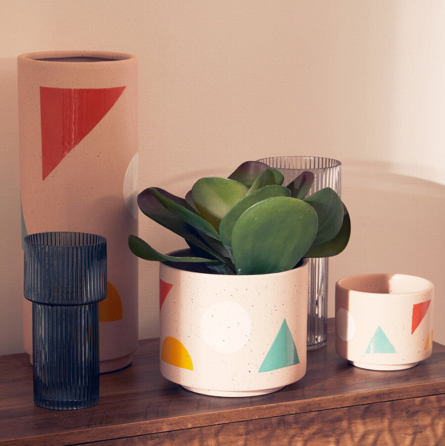 A jada small abstract white ceramic planter with speckled texture and colorful geometric decals holding a green succulent