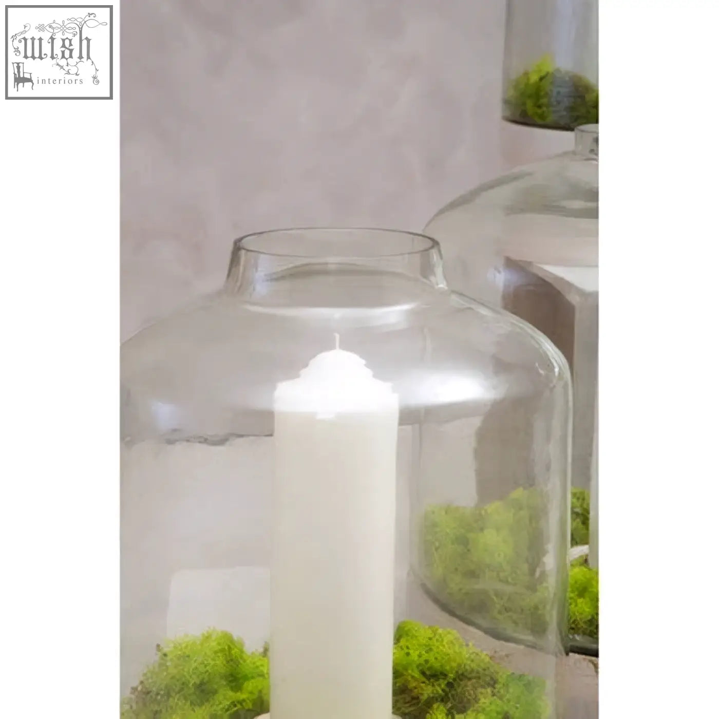 Clear glass jain large hurricane candle holder with white candle and green moss inside for decorative use