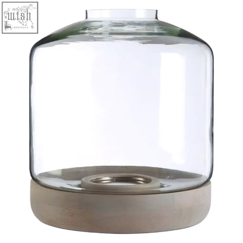 Clear glass jain large hurricane candle holder with a matte beige concrete base and metallic insert at the bottom