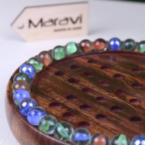 A jajur wooden solitaire game board with polished dark brown wood and colorful glass marbles for solitaire game fun