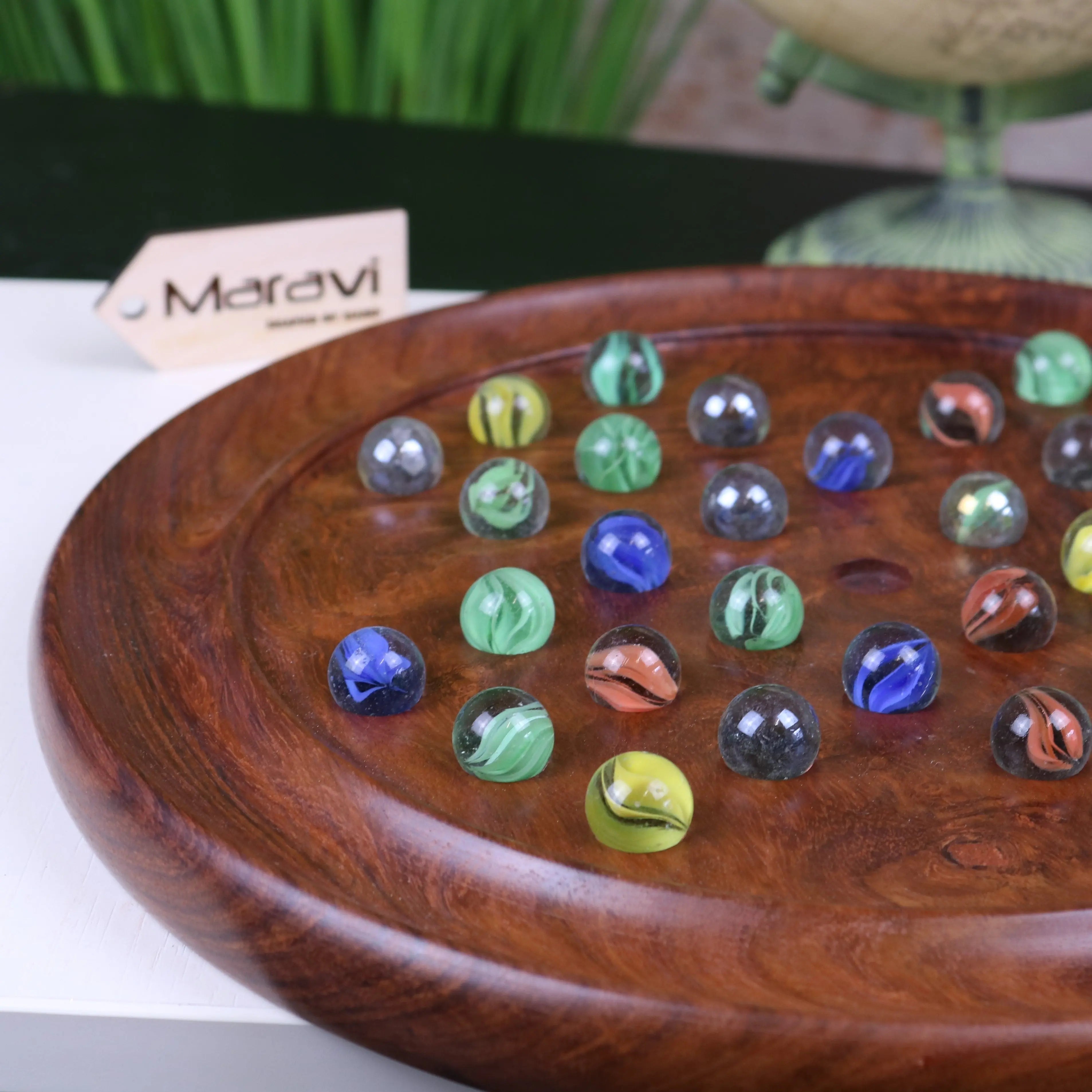 Colorful translucent glass marbles with swirling patterns on polished wood in jajur wooden solitaire game set