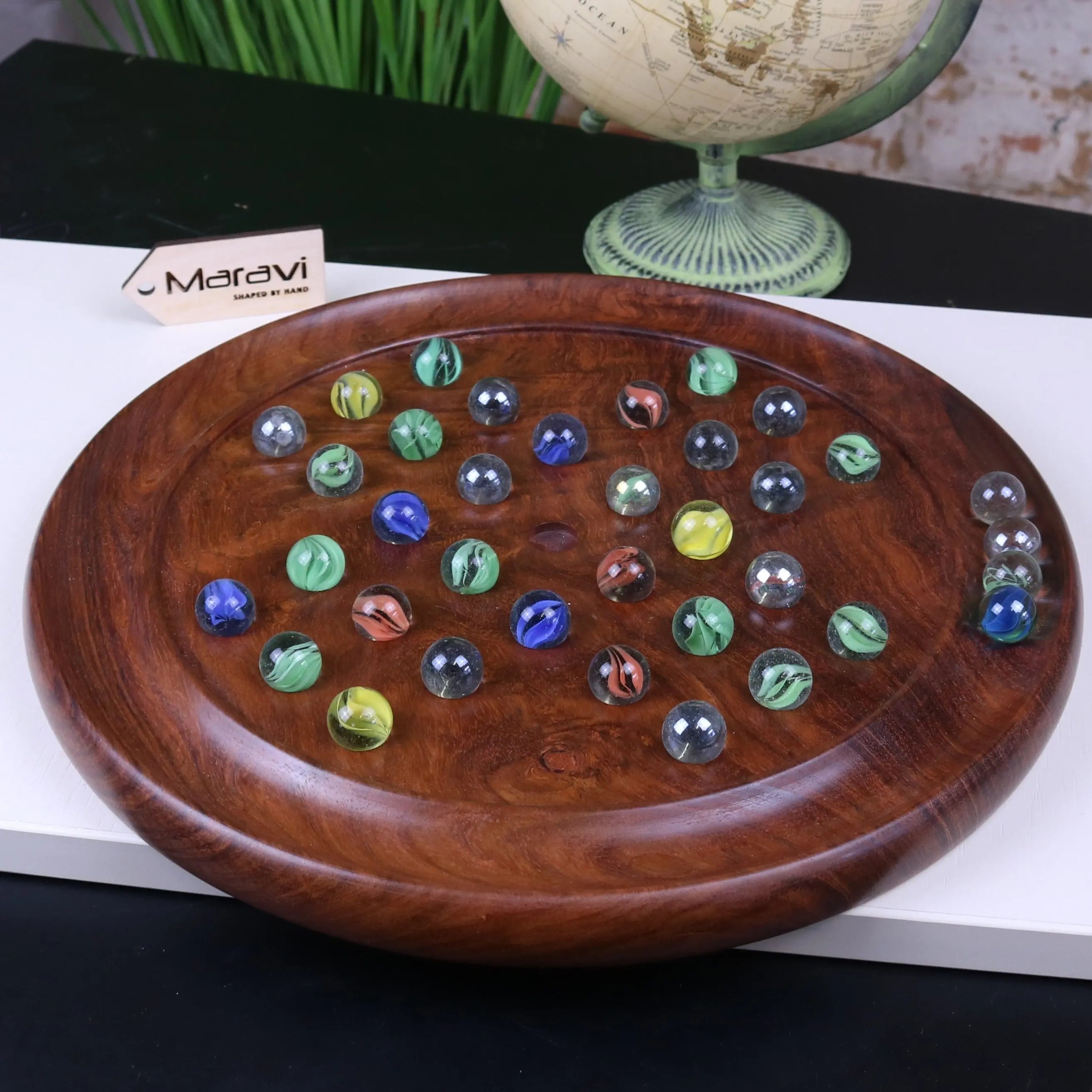 A polished dark brown wooden solitaire game board with colorful glass marbles for jajur wooden solitaire fun