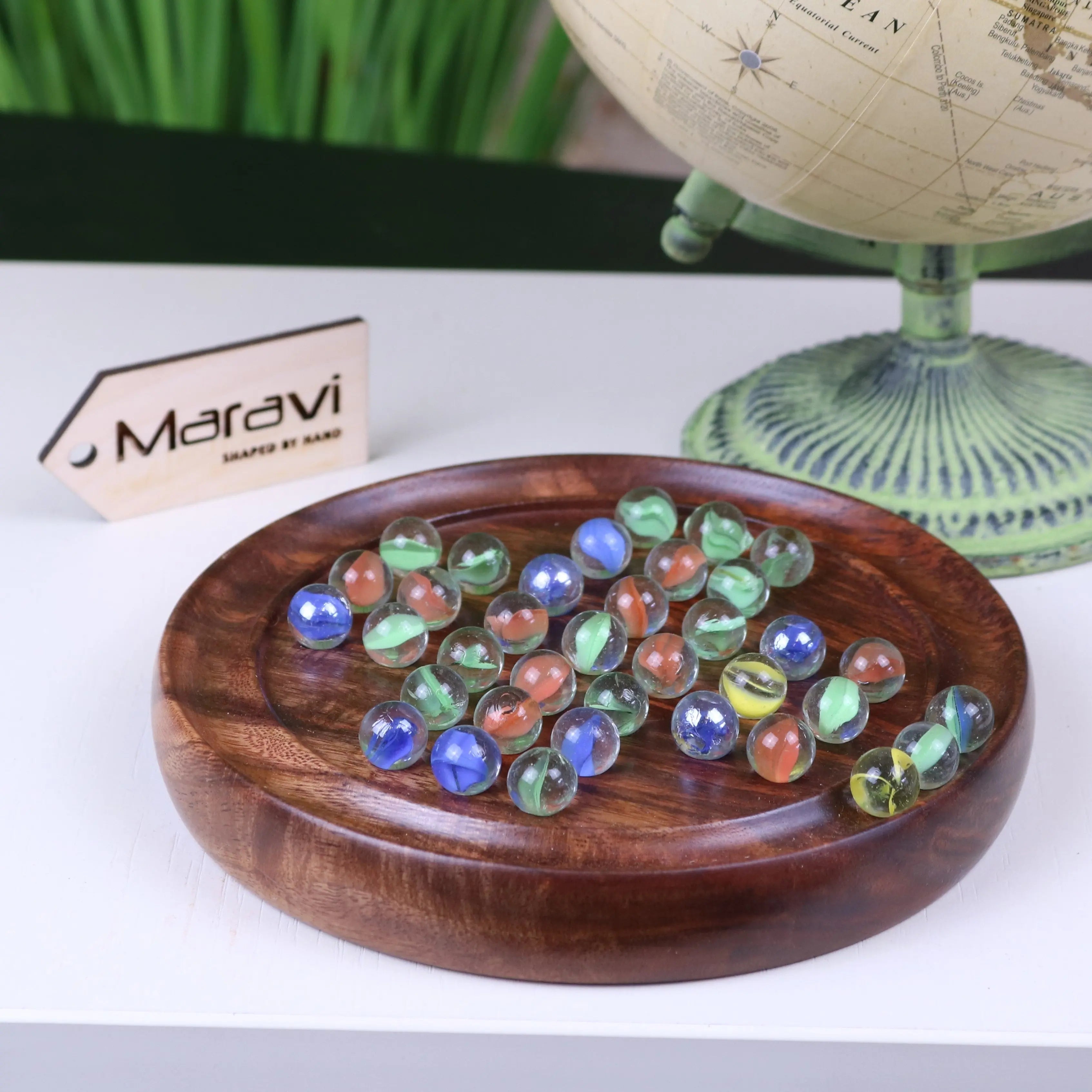 A jajur wooden solitaire game with colorful translucent glass marbles on a dark wood circular tray for solitaire game fun
