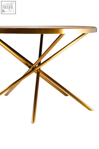 Jana round fir wood dining table with gold-finished metal circular top and intersecting splayed legs design