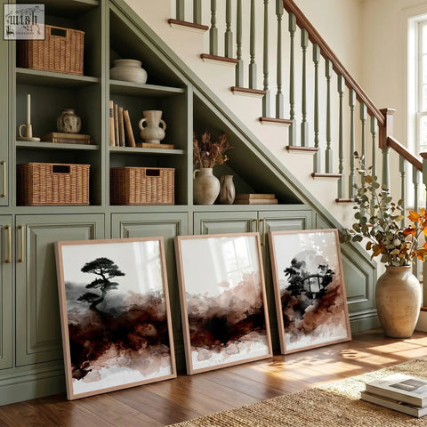 Three framed japanese wall art prints with earthy brown black and white ink wash in minimalist wooden frames leaning on a green cabinet