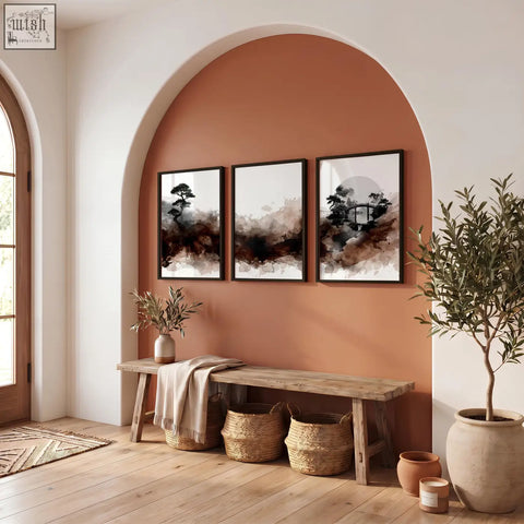 Three framed japanese wall art prints with black brown and white ink wash designs hang above a rustic wooden bench