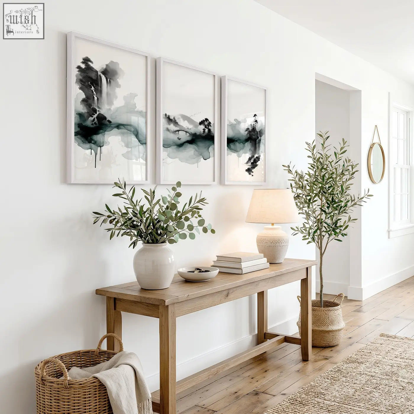 White ceramic vase with green eucalyptus branches next to japanese wall hangings ink wash landscape set of 3