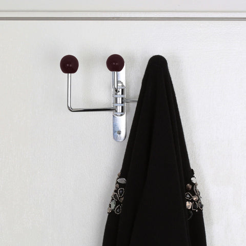 Chrome-plated double hook with jaxen purple ceramic balls holding a black garment on white wall