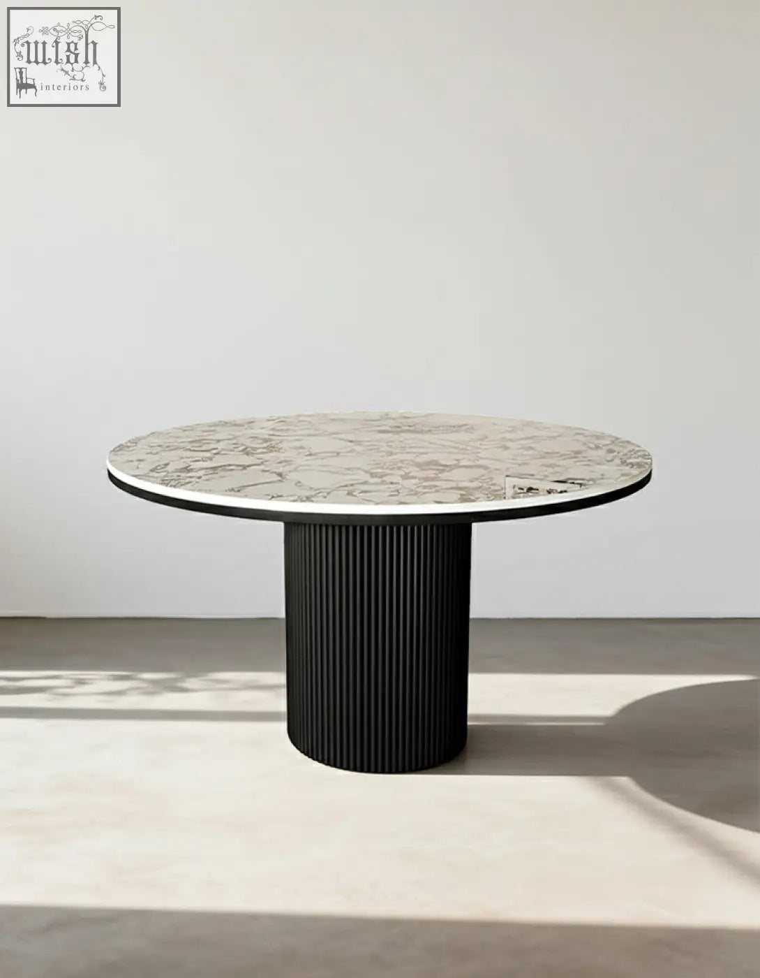 Modern round dining table with white marble top and black ribbed pedestal base perfect for round dining spaces
