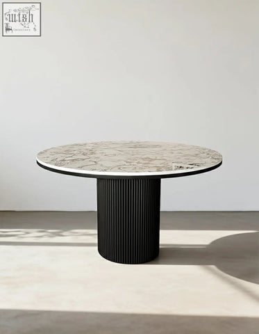 Modern round dining table with white marble top and black ribbed pedestal base perfect for round dining spaces