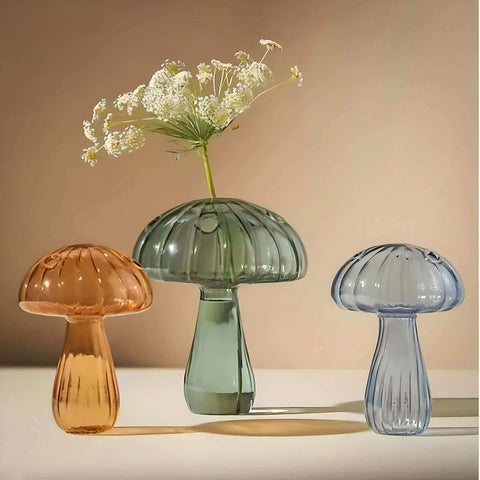 Three jelly mushroom vases in amber sage green and translucent blue glass with a mushroom vase design