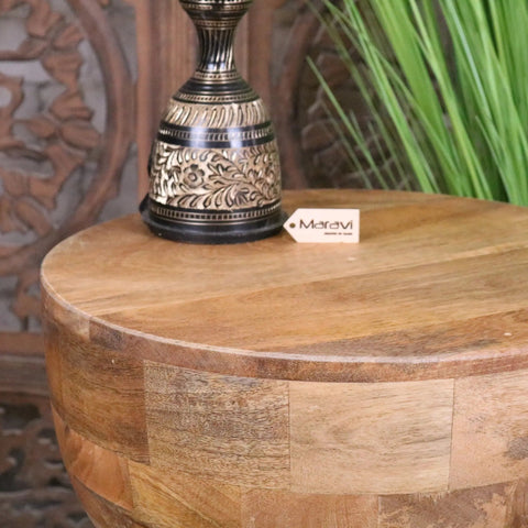 A decorative brass and black metal vase with floral engravings on a rustic jivana mango wood side table