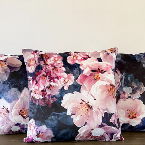 A high quality jolanda floral velvet cushion with vibrant pink and white blossoms on deep navy blue velvet background
