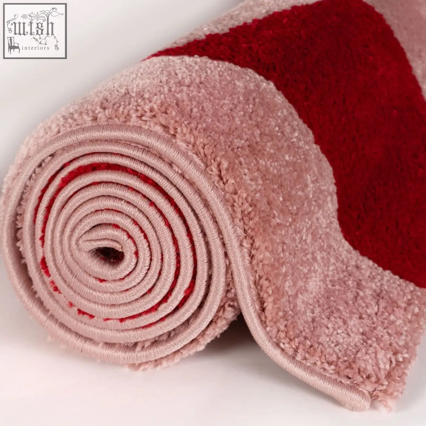 A plush rolled-up joli checkered red and pink rug featuring soft pink and vibrant red colors