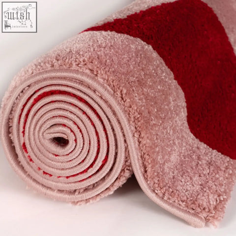 A plush rolled-up joli checkered red and pink rug featuring soft pink and vibrant red colors