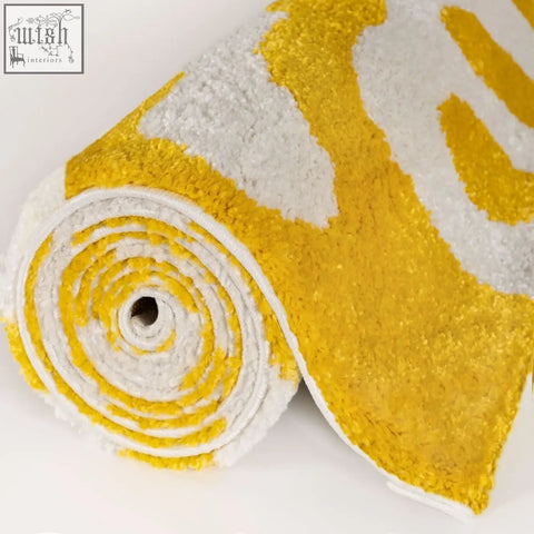 A plush rolled bath mat in bold yellow and white with a soft texture from the joli doodle yellow collection