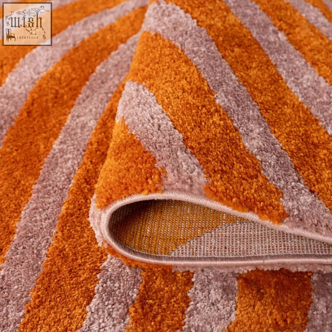 A joli striped orange plush rug with a flowing striped pattern in vibrant orange and soft mauve colors