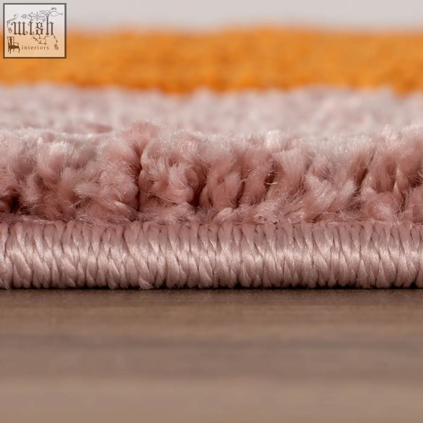 A plush joli striped orange rug in dusty rose with a soft textured pile and neatly stitched edge