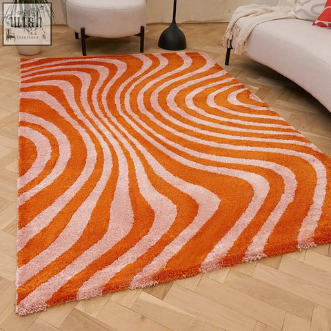Vibrant orange and blush pink joli striped rug with a flowing striped pattern and plush shag texture