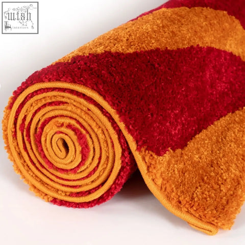 A plush joli wave red rug with bold flowing wave pattern in vibrant red and orange stripes rolled up neatly